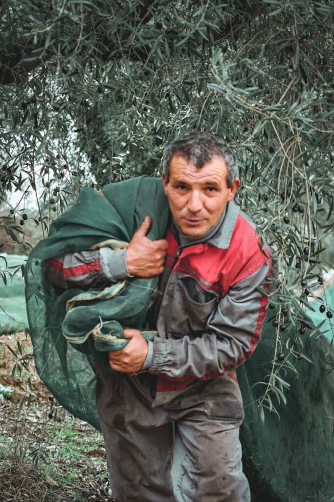 man in green jacket holding green plant